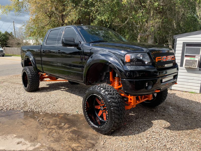 Black Ford F-150 lifted with orange accents